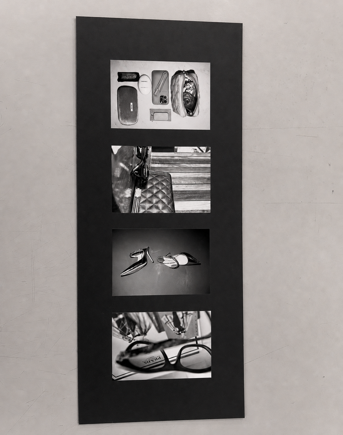 Four black-and-white fashion still-life photographs mounted vertically on a matte-black exhibition board.