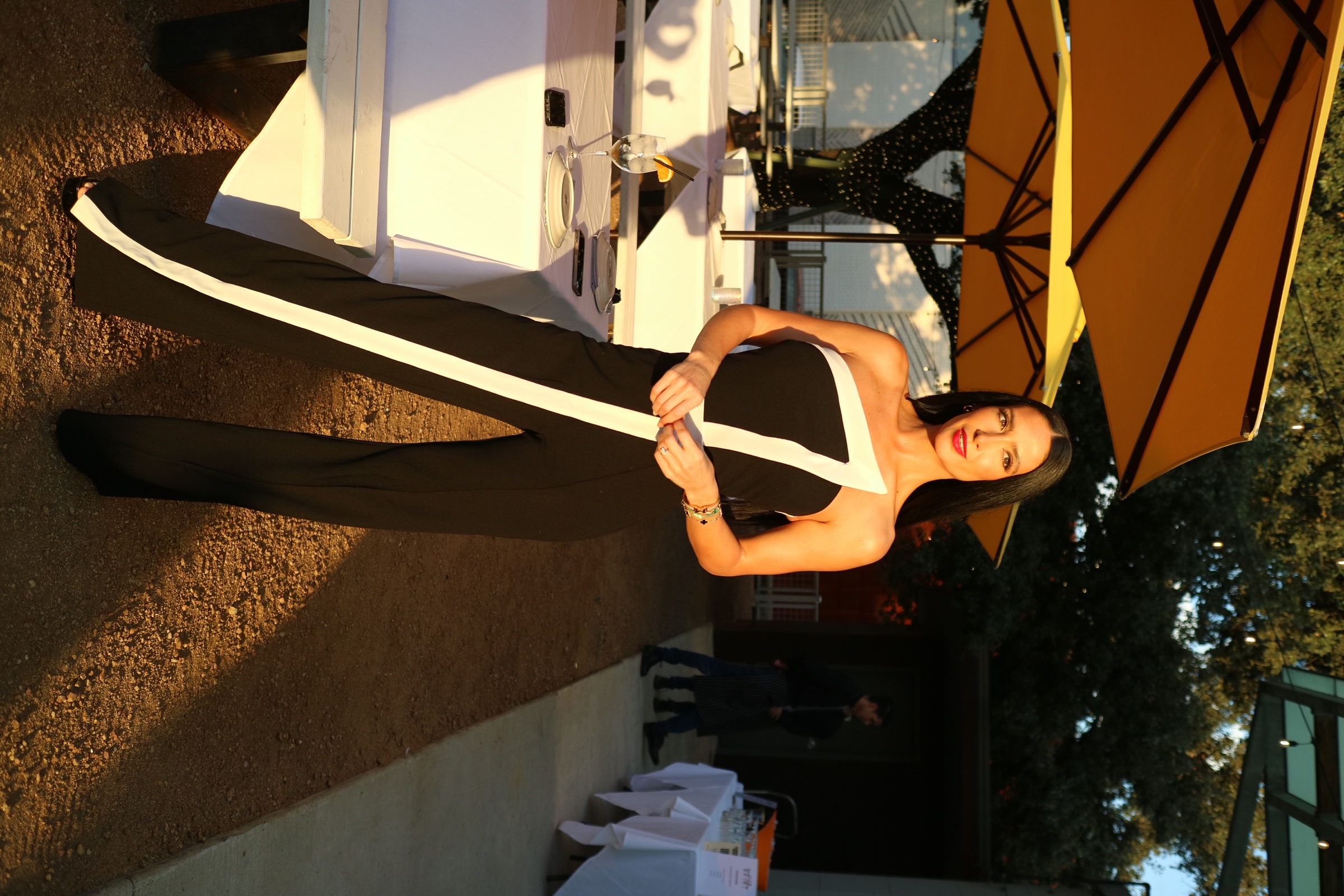 Outdoor portrait of a woman wearing a graphic black-and-white evening look in warm sunlight.