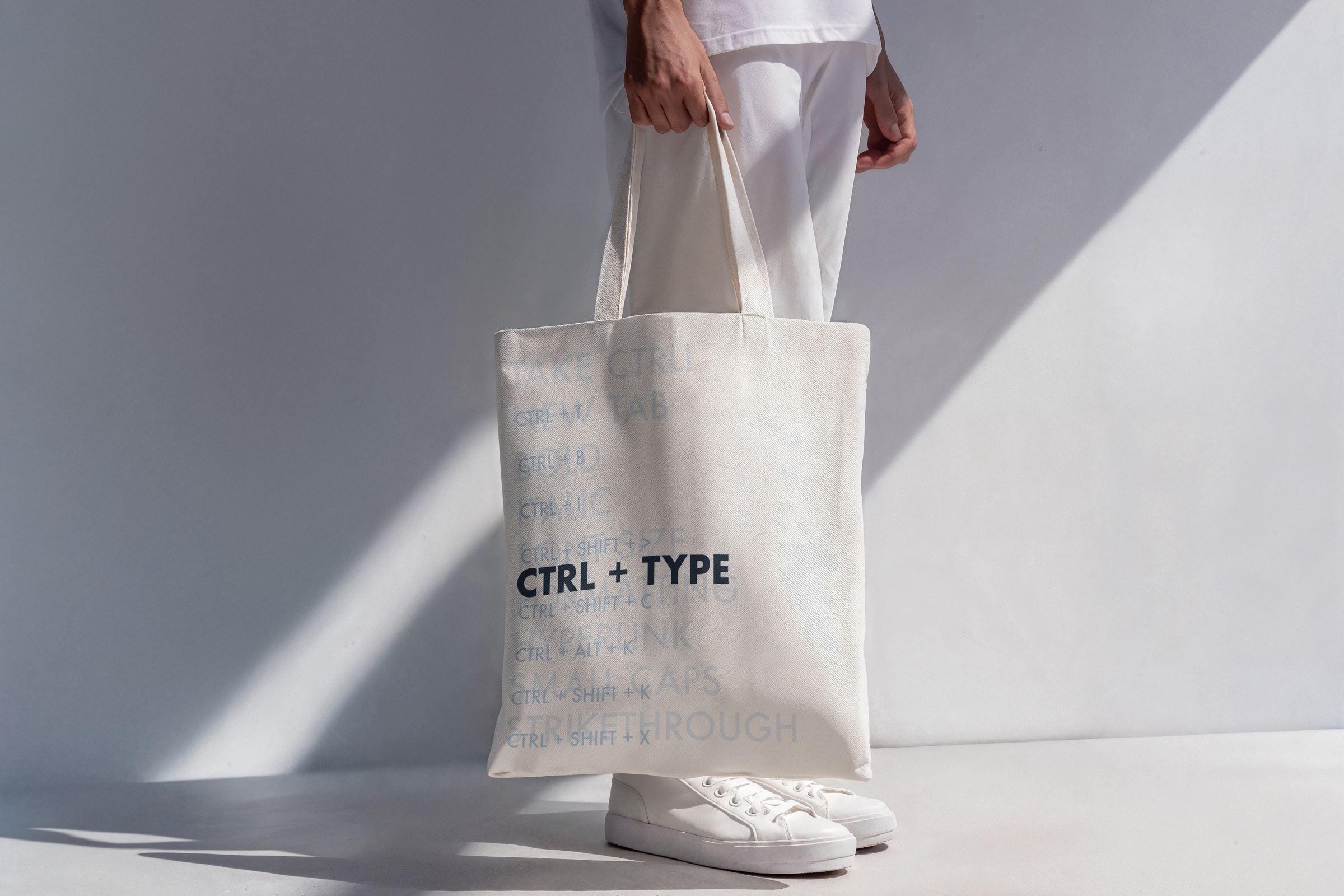 Cream tote bag carrying the CTRL + TYPE command-pattern exhibition identity.